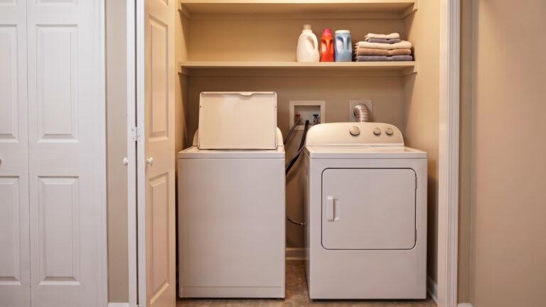 Small laundry closet with washer and dryer, limited storage space and an open appliance door showing why storage must preserve machine access.